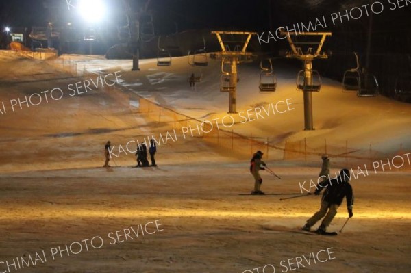 照明に照らされた幻想的なゲレンデを楽しむスキーヤー