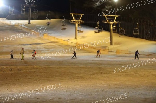 照明に照らされた幻想的なゲレンデを楽しむスキーヤー