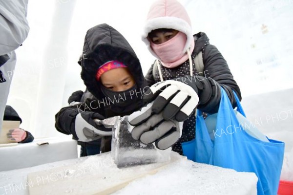 狙った角度で慎重に―。自分だけのアイスグラスを然別湖の氷から削り出す観光客