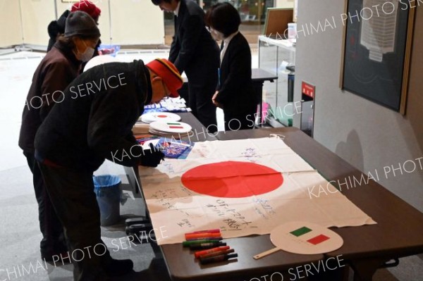 堀川選手を応援する国旗に寄せ書きする町民ら（７日午後１１時１０分）