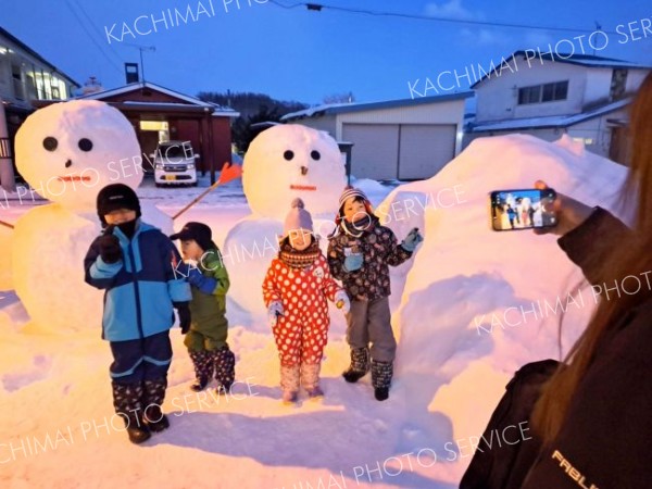 雪だるまと記念写真を撮る来場者