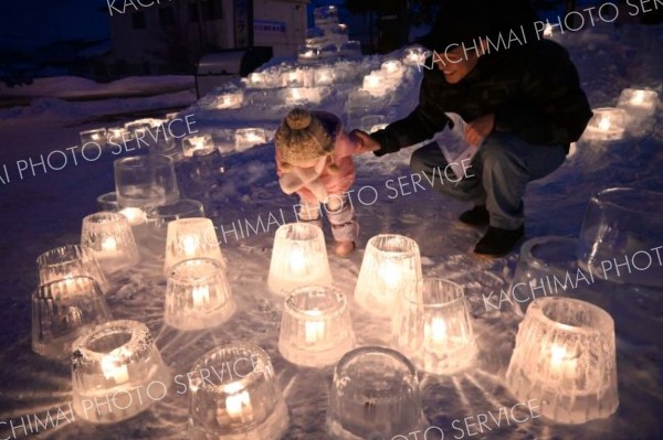 アイスキャンドルの柔らかな光を眺める親子