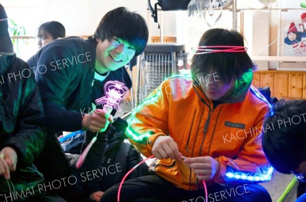 電飾や蛍光色を発するおもちゃを準備する参加者。壁やストーンに付け会場を彩る