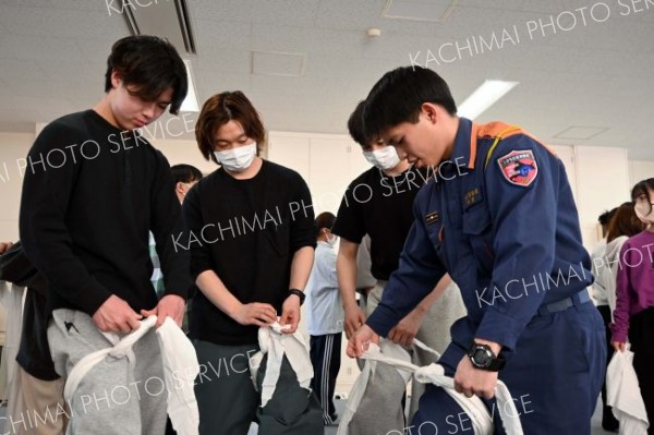 消防署員から三角巾を使った止血法などを学ぶ看護学生