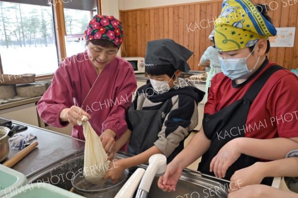 教えてもらいながら豆腐を作る児童