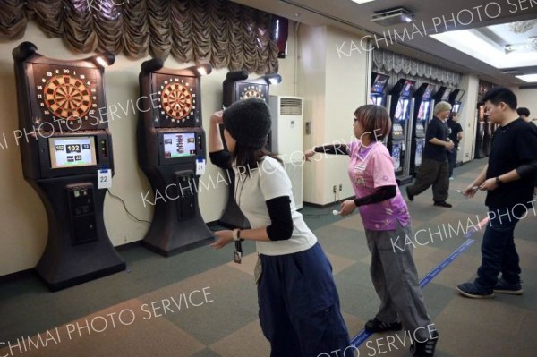 狙いを定めダーツの矢を放つ出場者ら