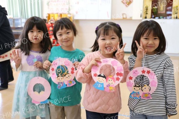 ひなまつりにちなんで制作した壁飾りを手に笑顔を向ける園児ら（帯広市内のさくら保育園、助川かおる通信員撮影）