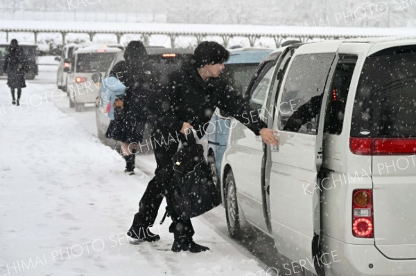 雪が降る中、保護者の送迎で受験会場へと向かう受験生（４日午前７時５０分ごろ、帯広緑陽高校。須貝拓也撮影）