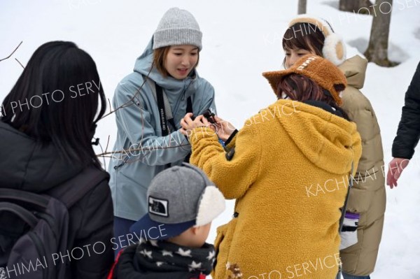 枝の先についた冬芽や葉痕の解説をする野表さん（中央）と、ルーペで拡大して観察する参加者ら