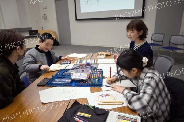 一緒に絵本の絵を描く児童ら