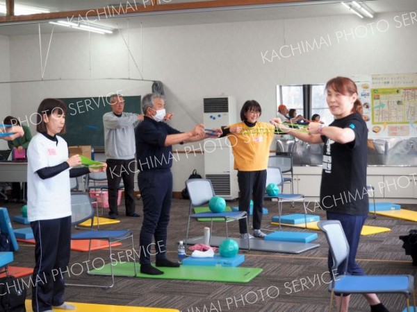 ゴムチューブを使いトレーニングをする参加者。